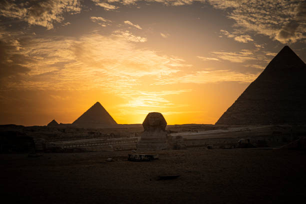 archaeological complex of great egyptian pyramids is located on the giza plateau. second pyramid of chephren khefren in the night light at sunset. sun sets behind the pyramid. sphinx at sunset - sphinx night pyramid cairo imagens e fotografias de stock