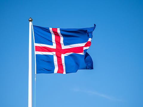 Flag of Iceland waving on the wind with blue sky background