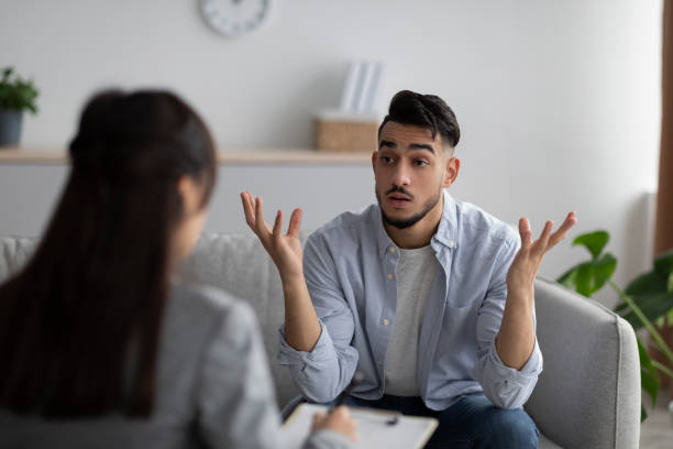 emotional arab man having session with psychologist, sitting on couch in counselor's office, seeking professional help - couple therapy alternative therapy relationship difficulties imagens e fotografias de stock