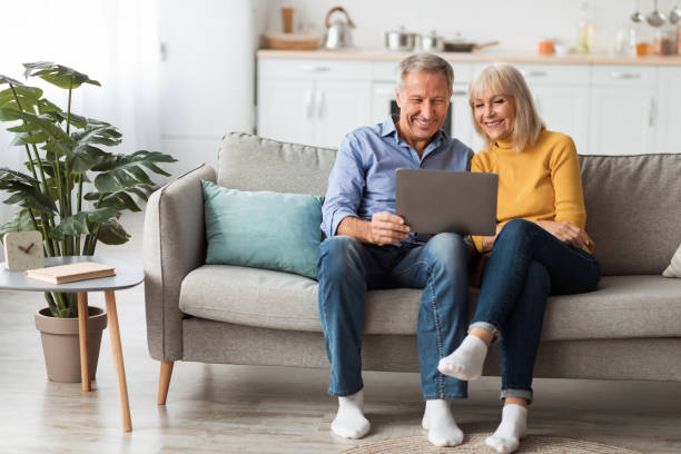 istock Cheerful Senior Spouses Using Laptop Watching Movie Onilne At Home 1368589683