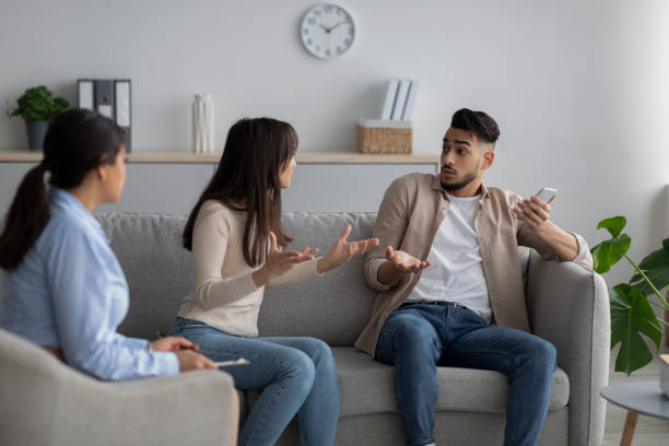 istock Angry arab lady complaining about her husband's smartphone addiction, sitting at psychologist's consultation 1368589727