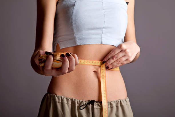 istock Beautiful strong women's abs with metre and burger. 136859012