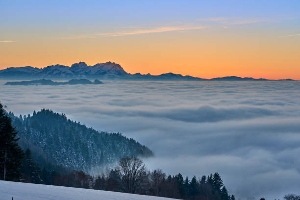 sunset in the snowy Bregenzer Wald area of Vorarlberg, Austria with spectacular view on Mount Saentis in switzerland above a sea of fog, taken in Sulzberg, Austria, landscape