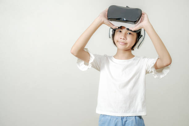 Smiling girl with glasses of virtual reality,VR application test Asian child girl with virtual reality glasses headset touching air during the VR experience, asia children and learning with virtual reality simulator application test stock photo