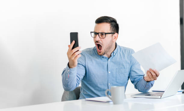 angry disagreeable businessman sitting at the desk talking online video conference call making unpleasant discussion arguing confronting opinion decision or idea unsatisfied results deadline shouting - frustration computer confusion businessman imagens e fotografias de stock