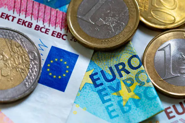 European union cash : detail of various euro banknotes and coins. Close-up shot with the word "euro", the EU flag, along with 50 cents, 1 and 2 euro coins