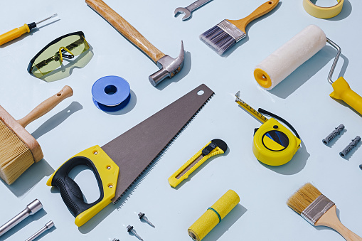 Flat lay still life of a large selection of assorted workshop tools and hardware arranged diagonally over blue