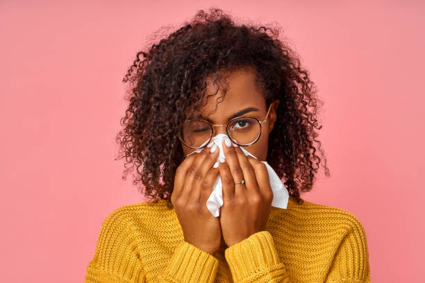 sick african american woman sneezes in white tissue, suffers from rhinitis and running nose - allergy sneezing cold and flu flu virus imagens e fotografias de stock