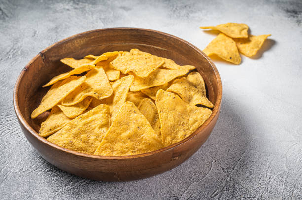 istock Mexican nachos corn chips in a wooden plate. White background. Top view 1368601027
