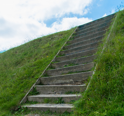 A staircase leading down to a green forest and meadow area. Photographed at Externsteine, Germany.