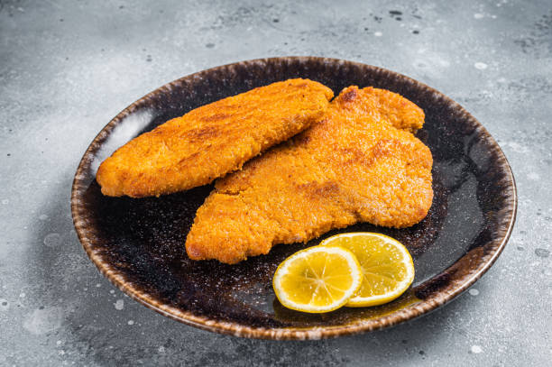 istock Roasted breaded german weiner schnitzel on a plate. Gray background. Top view 1368605399