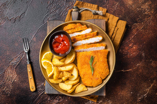 Breaded german weiner schnitzel with potato wedges. Dark background. Top view Breaded german weiner schnitzel with potato wedges. Dark background. Top view. chicken steak stock pictures, royalty-free photos & images