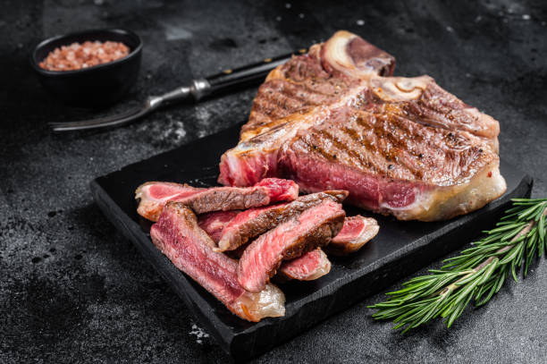 istock T bone grilled beef meat Steak, cooked Porterhouse on a marble board. Black background. Top view 1368605706