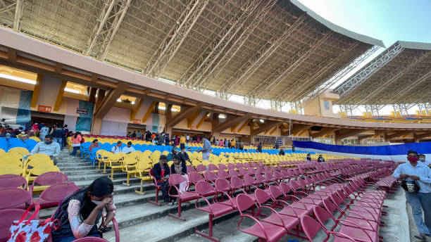 Stadium stands remain empty and dirty, filled with scattered debris after a soccer game. Broken chairs and discarded items reflect the neglect following the event.