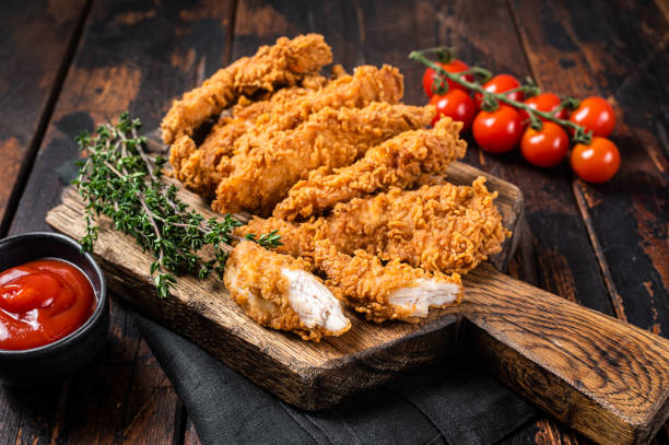 strisce di pollo impanate fritte croccanti, filetto di petto con ketchup di pomodoro su un piatto. backgrund in legno. vista dall'alto - croccante foto e immagini stock