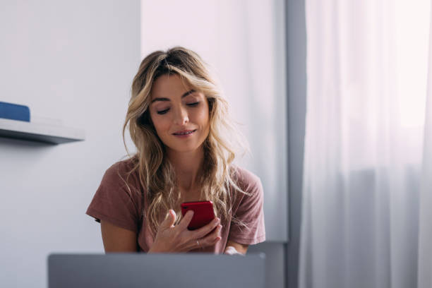 istock Blonde Female Working From Home On Her Bed and Using Her Mobile Phone 1368608533