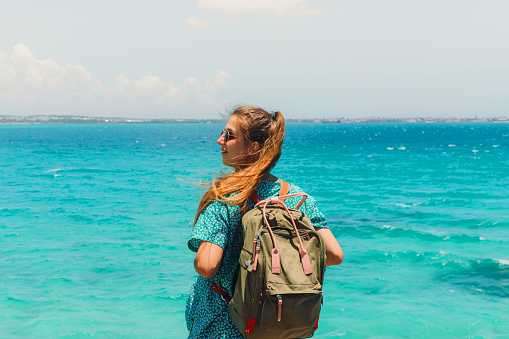 Young woman backpacker traveling in Tanzania, enjoying a view of the crystal blue Indian Ocean