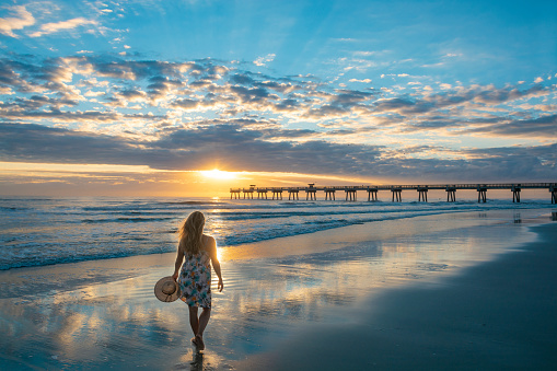 Mujer caminando en la hermosa playa al amanecer. photo