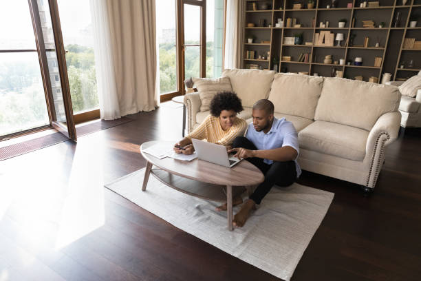 Young African American married couple maintaining family budget Young African American married couple maintaining family budget, using finance app on laptop computer, calculating money, paying paper bills, invoice, doing domestic paperwork at home. Wide shot wide shot stock pictures, royalty-free photos & images