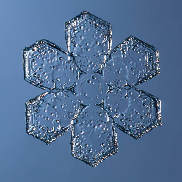 Snowflake on smooth gradient background grey to blue : macro photo of real snow crystal on glass surface. This is small snowflake with unusual pattern.