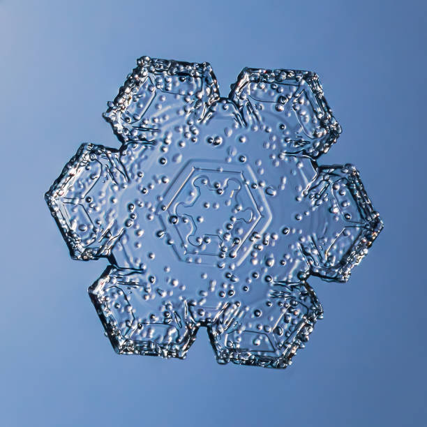 Snowflake on smooth gradient background grey to blue : macro photo of real snow crystal on glass surface. This is small snowflake with unusual pattern.
