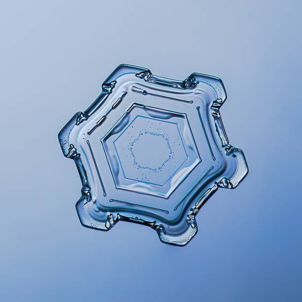 Snowflake on smooth gradient background grey to blue : macro photo of real snow crystal on glass surface. This is small snowflake with unusual pattern.