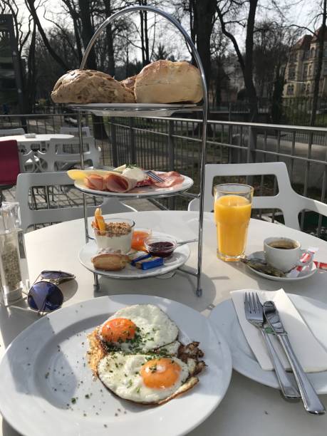 istock Lunch Dinner - Breakfast Etagere Fried Egg Orange Juice Rolls Honey Yogurt Muesli Coffee Ham Cheese Spread cheese Sunglasses Salt Pepper 1368614710