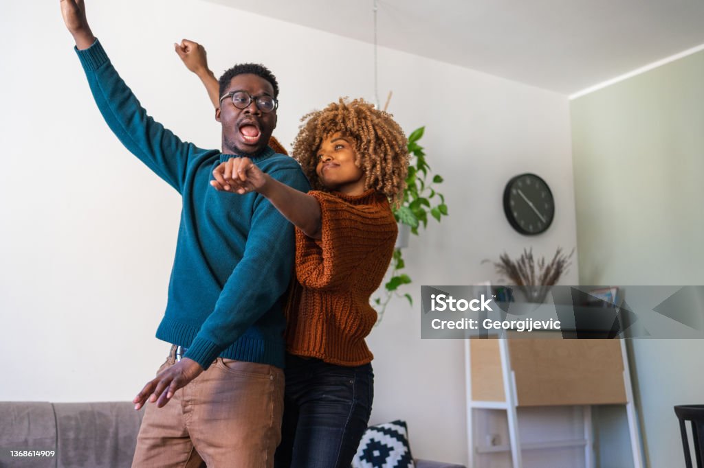 Happy dance A young African-American couple dances around the house. They look happy in love celebrating their achievements. Couple - Relationship Stock Photo