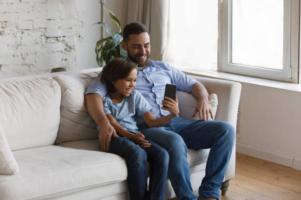 istock Happy teen kid using cellphone with young father. 1368615093