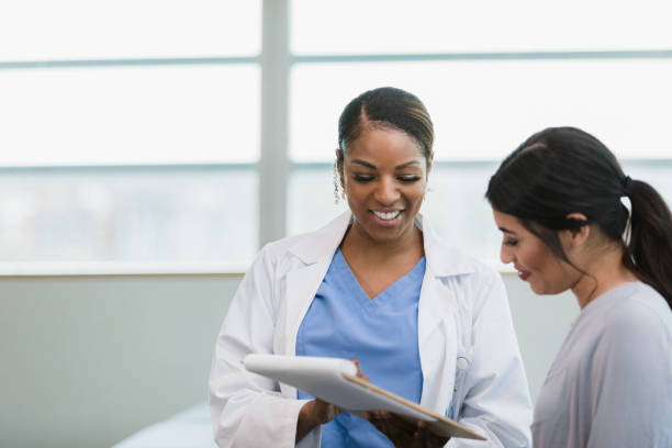 doctora sonriente y paciente feliz leen el historial médico - nurse student black healthcare and medicine fotografías e imágenes de stock