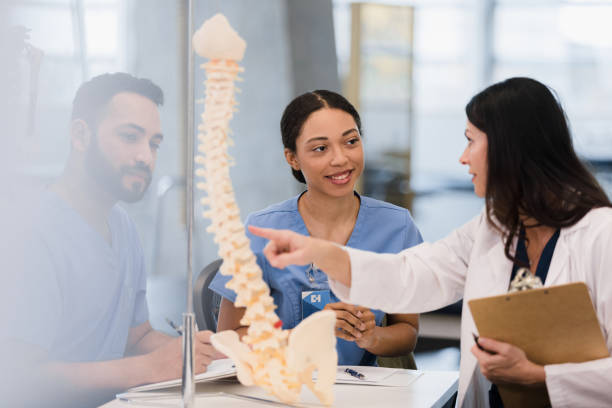 istock Two nursing students listen and learn from female teacher 1368615546