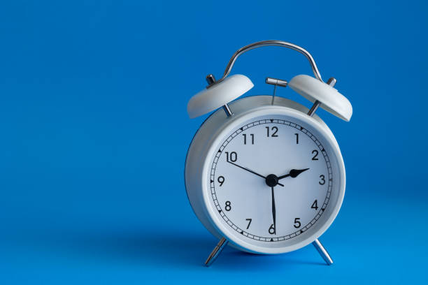 istock Isolated white alarm clock on vibrant blue background 1368617761