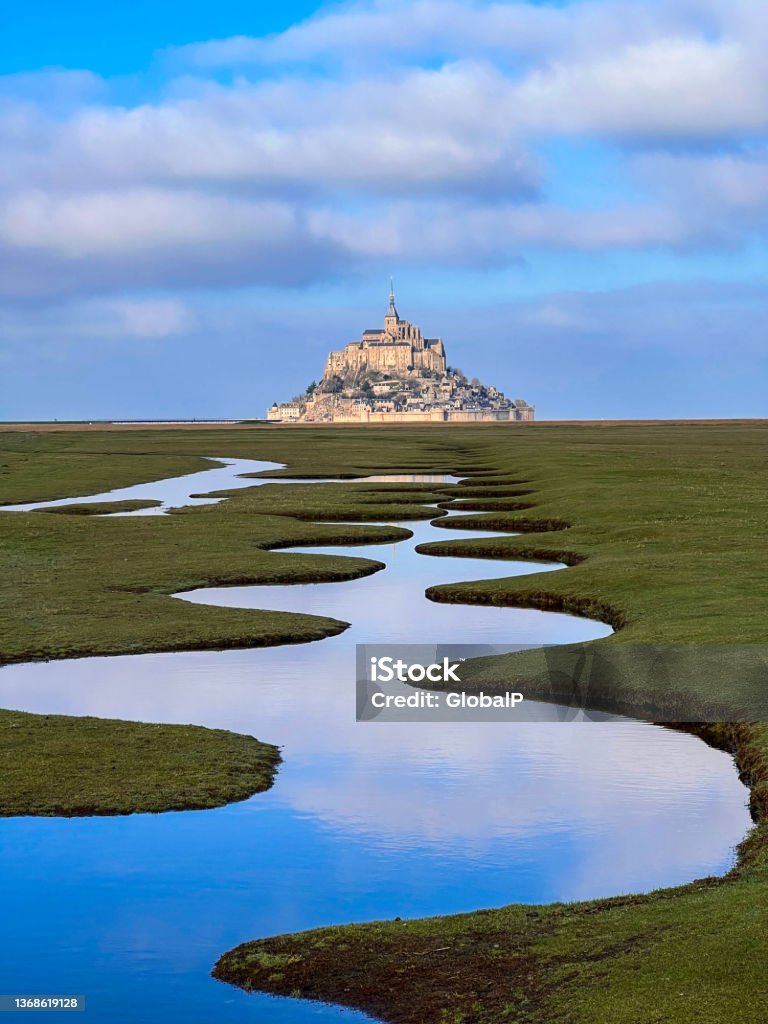 Salt marsh and Mont Saint-Michel landscape in normandy during sunny and cloudy day, UNESCO World Heritage Site in France, Europe. Mont Saint-Michel Stock Photo