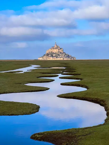 Photo of Salt marsh and Mont Saint-Michel landscape in normandy during sunny and cloudy day, UNESCO World Heritage Site in France, Europe.