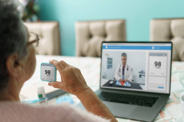 Senior woman at home with medical device and teleconsulting stock photo