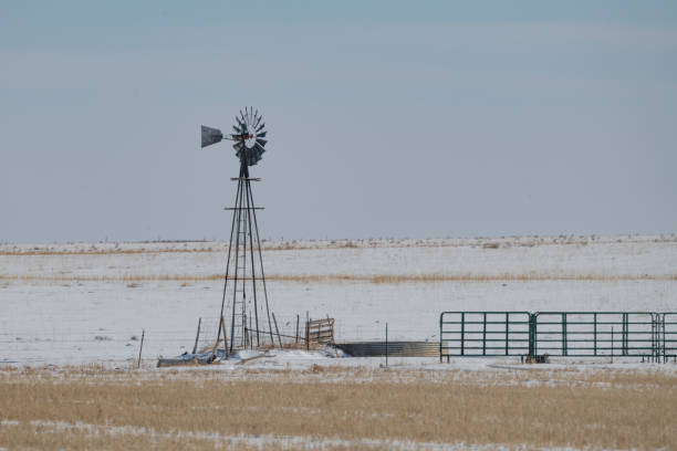 istock Windmill and old barbed wire fence on ranch land with snow 1368630357