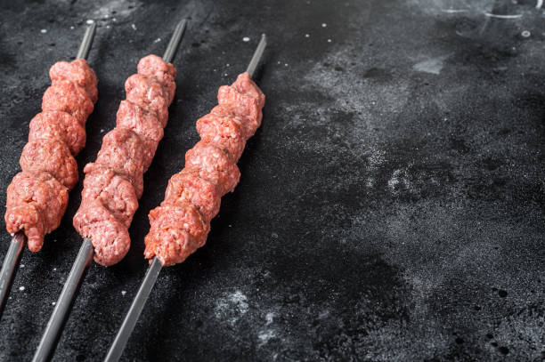 istock Raw mince lamb meat shish kebab on butcher table. Black background. Top view. Copy space 1368631465