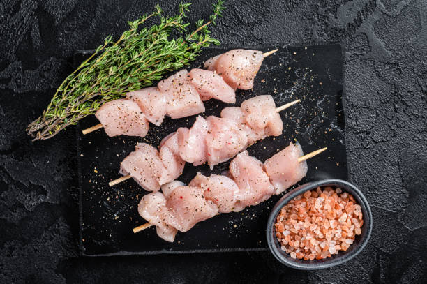 istock Raw chicken meat shish kebab skewers. Black background. Top view 1368631649