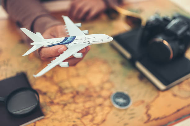 istock Hands playing model airplane to fly above world map and book, magnifying glass, compass and camera on map. Travel , Adventure and Discovery concept. map by Compart maps http://www.mapsales.com/compart-maps/world-wall-maps/antique-world-wall-map.aspx 1368631683