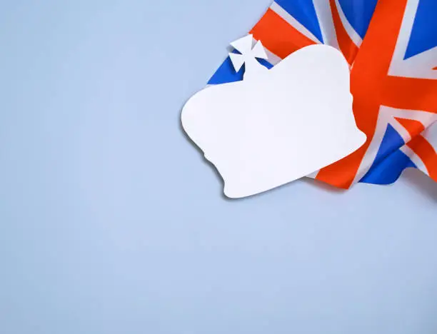 paper silhouette of the british royal crown on the background of the flag of the united kingdom of great britain and northern ireland