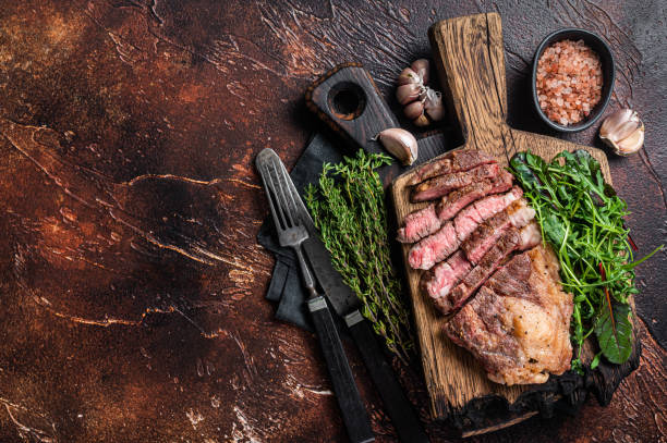 istock Grilled Chuck Roll beef steak with salad on wooden board. Dark background. Top view. Copy space 1368632140