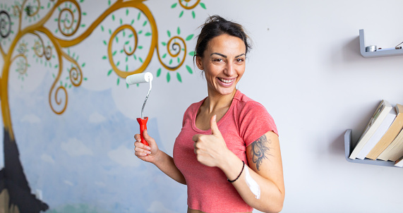 Portrait of confident and charming young female artist painting the mural at the nursery