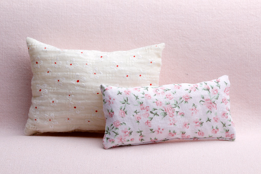 Cozy cushions with flower pattern on pink sofa