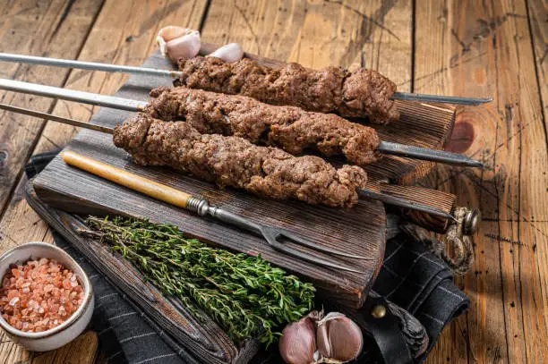 BBQ Grilled Adana kebab on skewers from minced lamb beef meat. Wooden background. Top view.