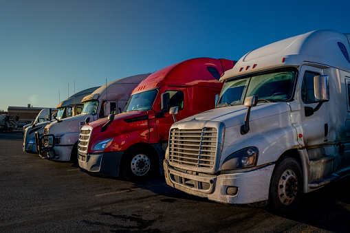 Three Red and White Semi-trucks parked in a lot ready to move cargo across the country