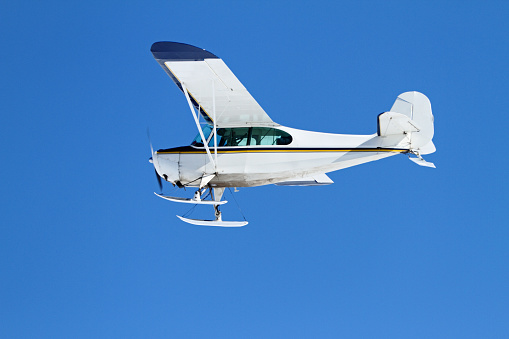 Aronca 7AC Fitted with skis flying in a clear blue sky.