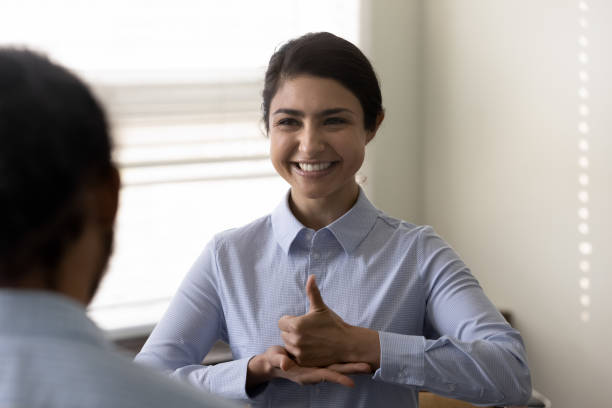 Smiling young Indian woman who is deaf using sign language Smiling young Indian woman who is deaf using sign language, communicating with friend or doctor physician, happy attractive female having fun and enjoying pleasant conversation, hard of hearing sign language stock pictures, royalty-free photos & images