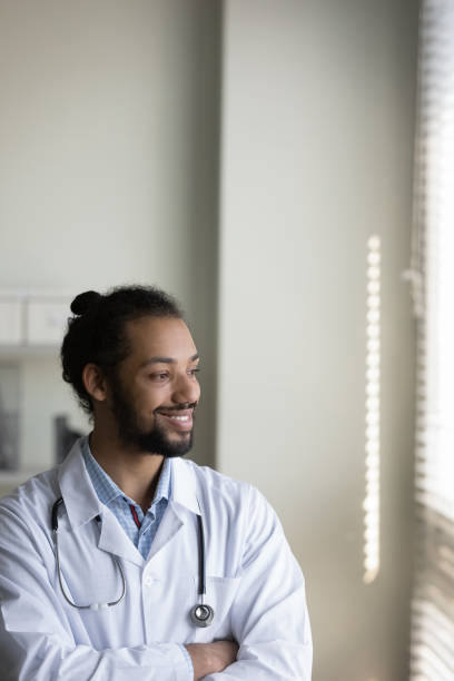 foto vertical sonriendo hombre afroamericano médico mirando a lo lejos - doctor thinking asking pensive fotografías e imágenes de stock