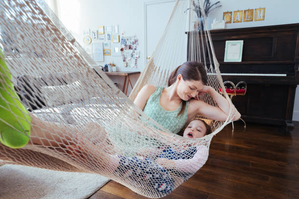 Mother spending quality time with her daughter relaxing in the hammock in their living room