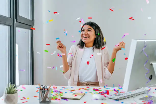 Photo of Young business woman having fun time catching confetti